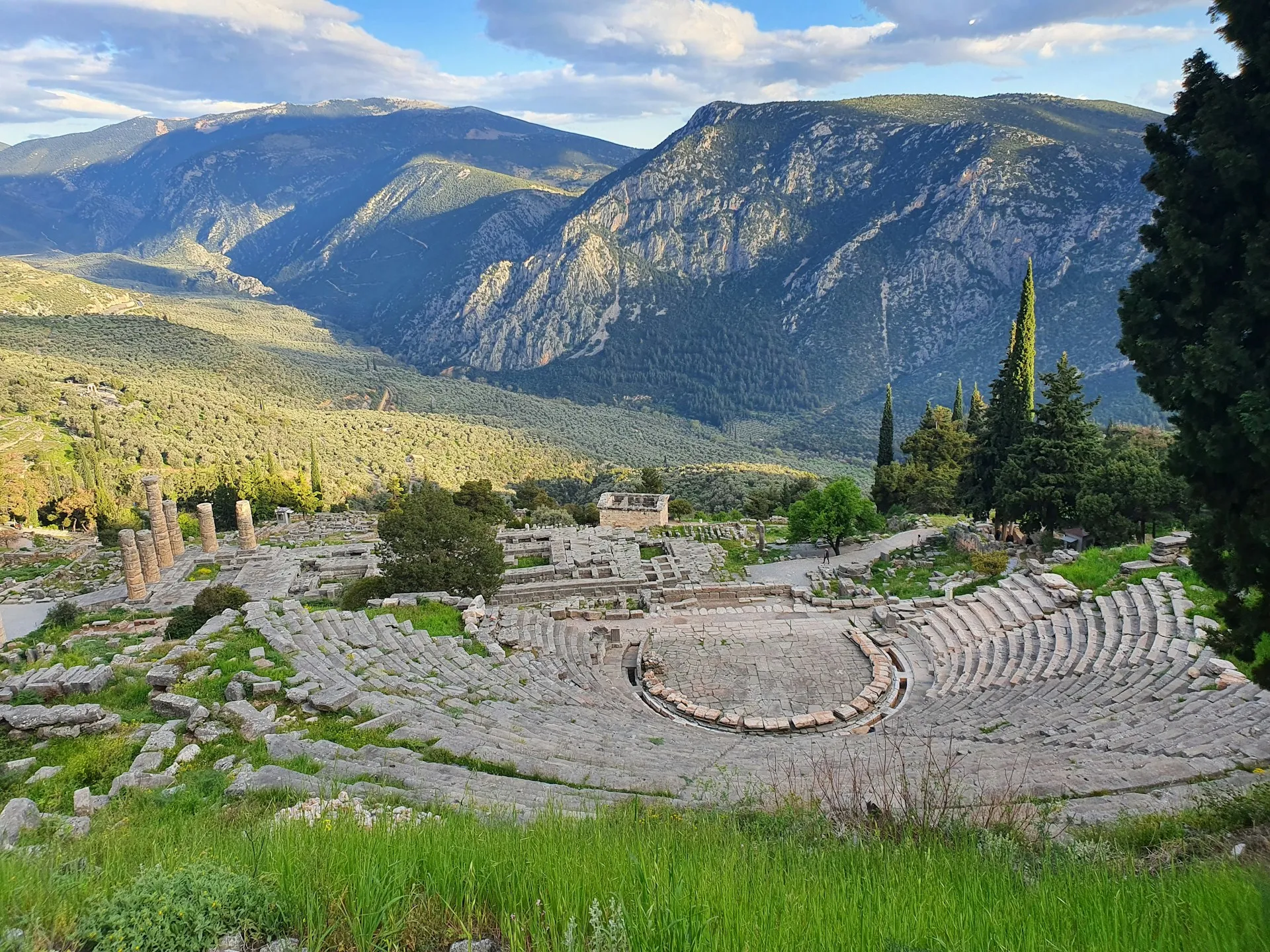 Ancient theater and ruins at Delphi set below steep mountain slopes.