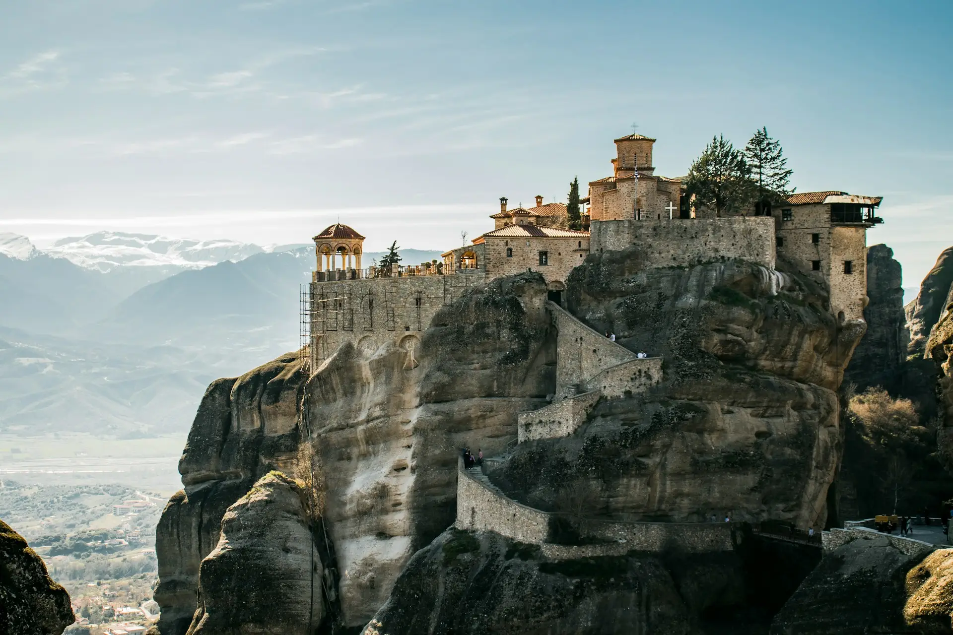 Monastery perched atop a rock pillar at Meteora with the valley and mountains in the distance.
